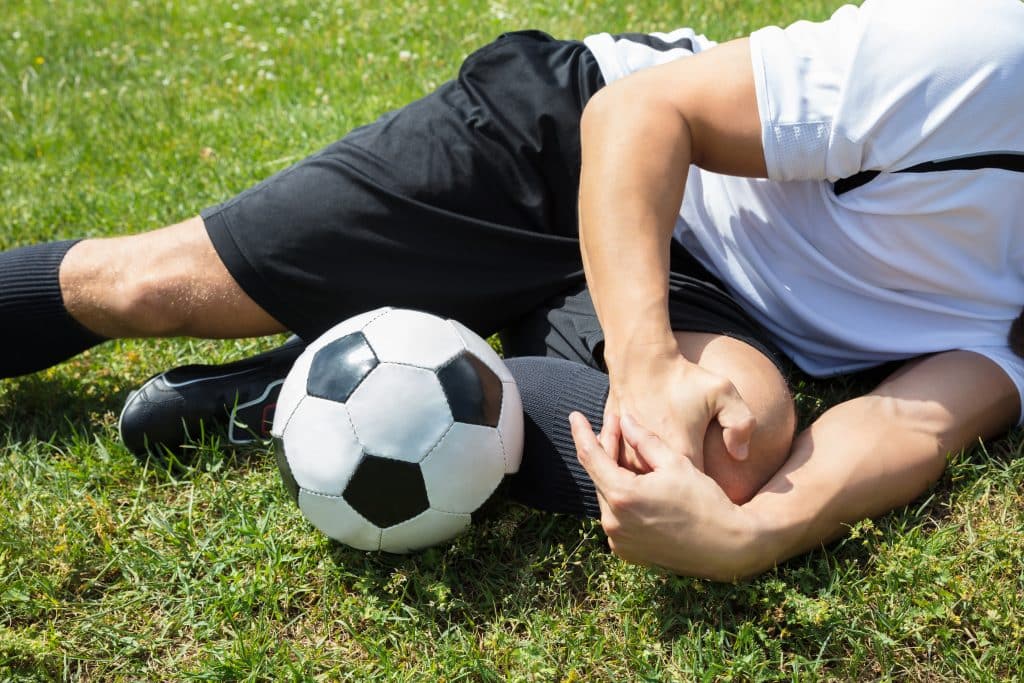 A soccer play on the ground holding his injured knee