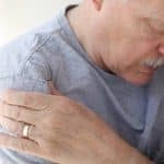 a senior man squeezes his arm due to pain caused by loose bodies in the shoulder
