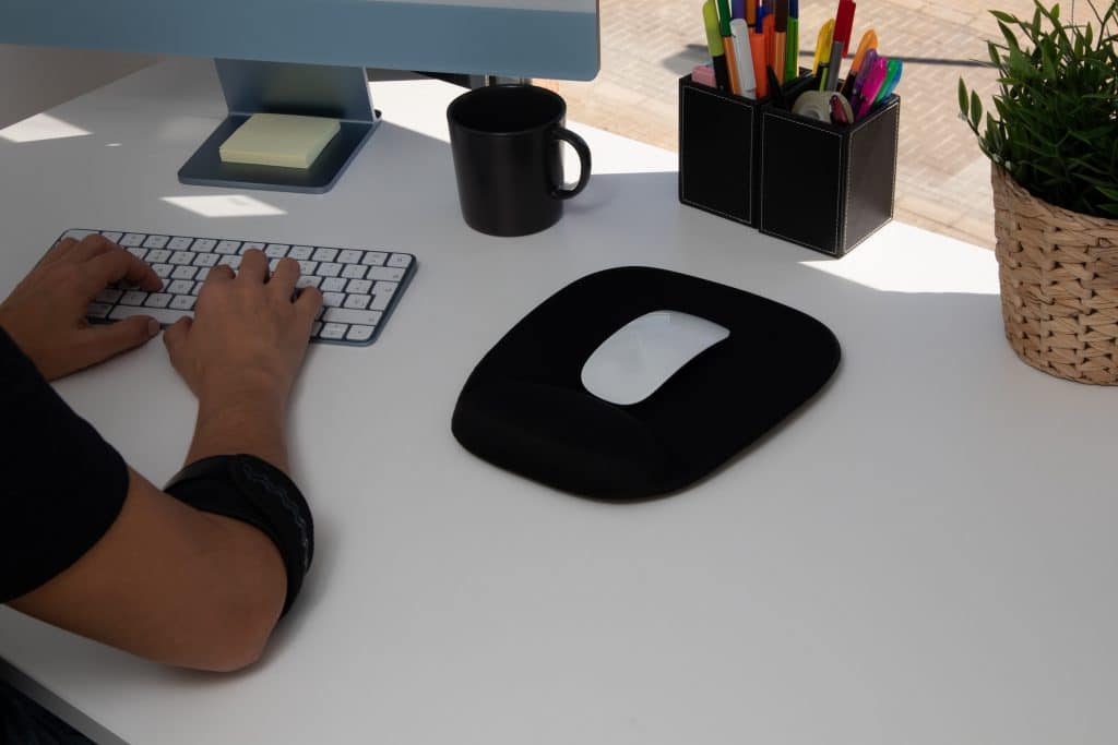 person working at a desk with an elbow pad for elbow pain