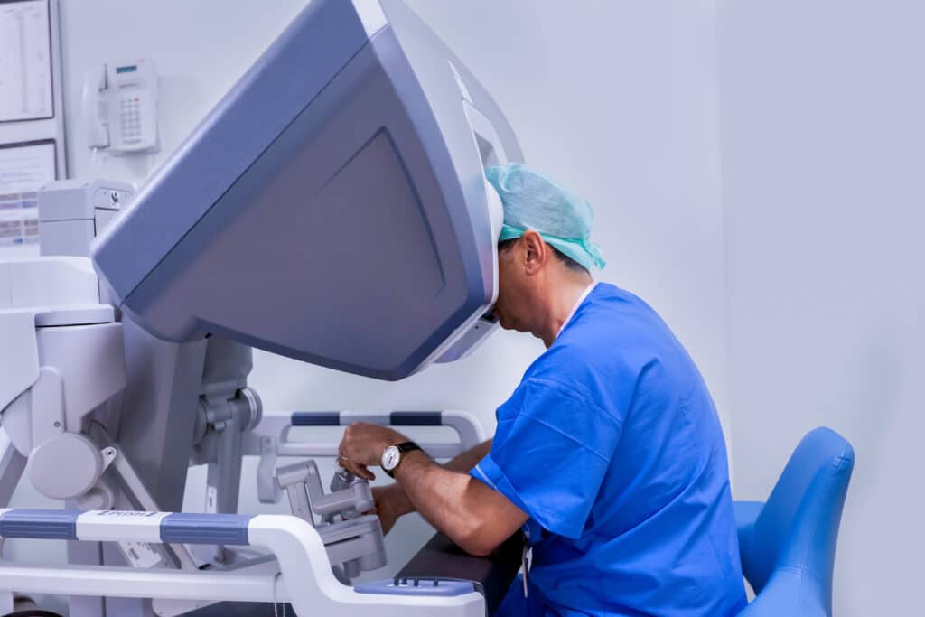 An orthopedic hip surgeon performing a total hip replacement surgery using a robotic device that allows him to position surgical tools and prosthetic joints.