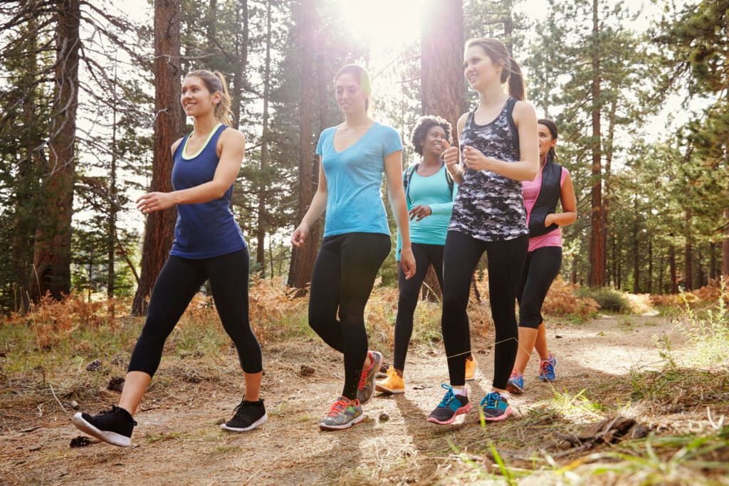 A group of women walking together on a trail as a way to prevent and treat back and spine pain.