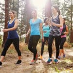 A group of women walking together on a trail as a way to prevent and treat back and spine pain.