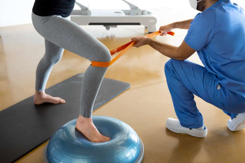 A person doing exercises with the help of a physical therapist after total knee replacement.
