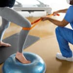 A person doing exercises with the help of a physical therapist after total knee replacement.