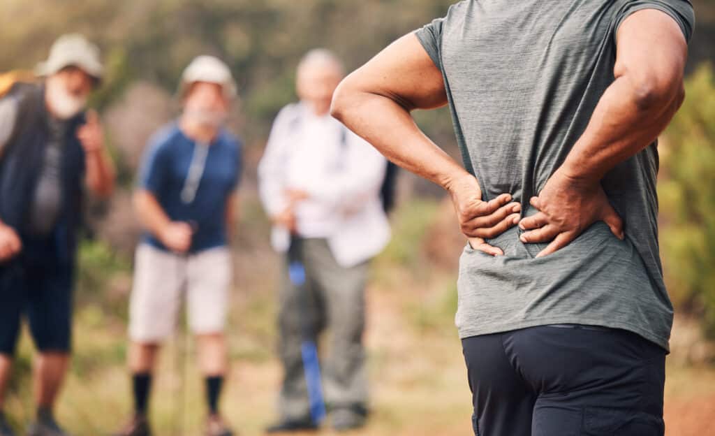 A man going on a hike with friends for lower back pain self-care.