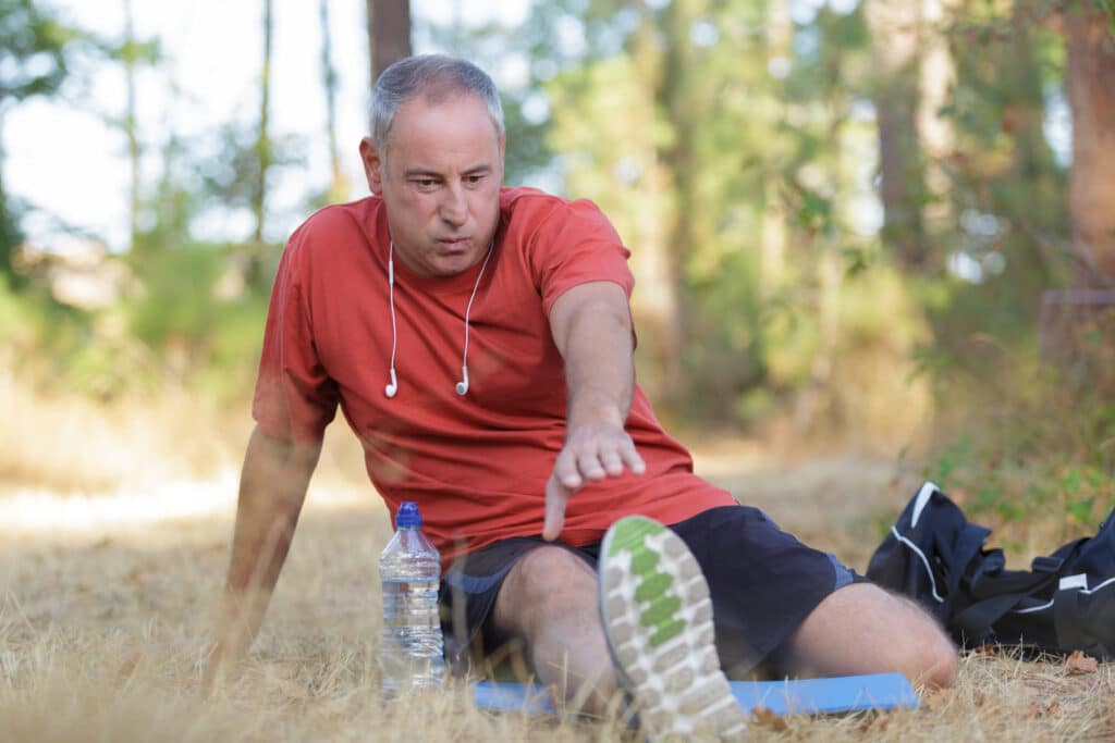 Runner performing a hamstring stretch for injury prevention while outdoors.