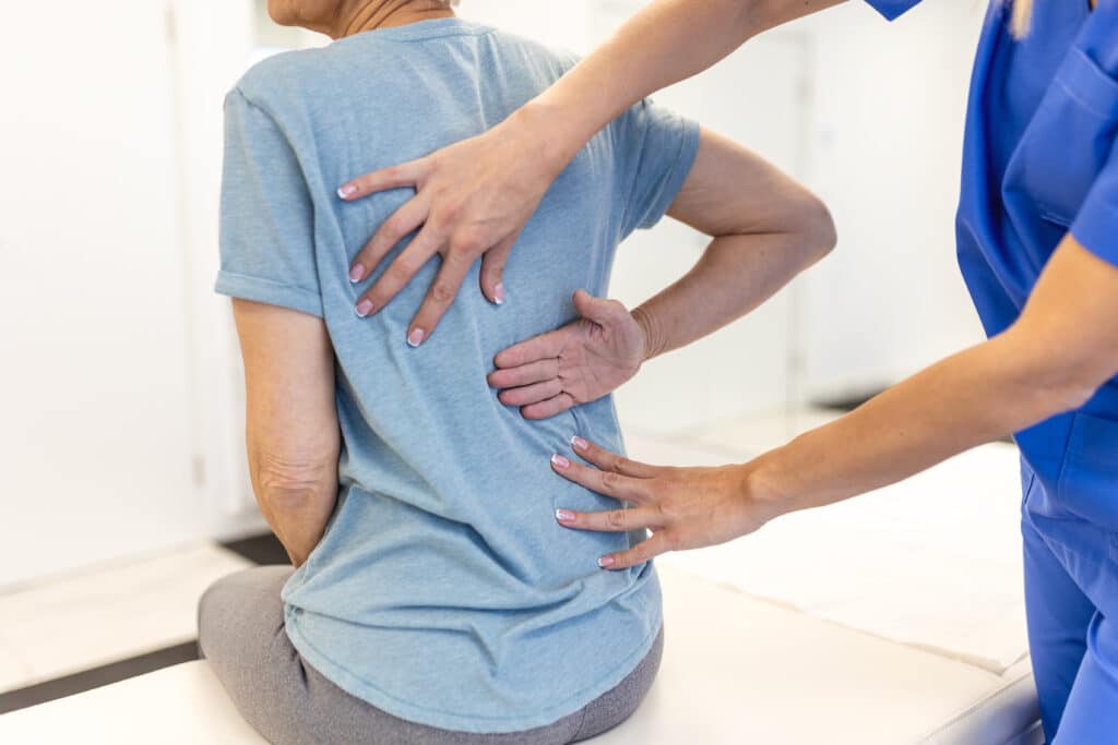 A person showing their back pain specialist where their back spasm is causing pain.