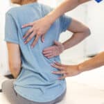 A person showing their back pain specialist where their back spasm is causing pain.