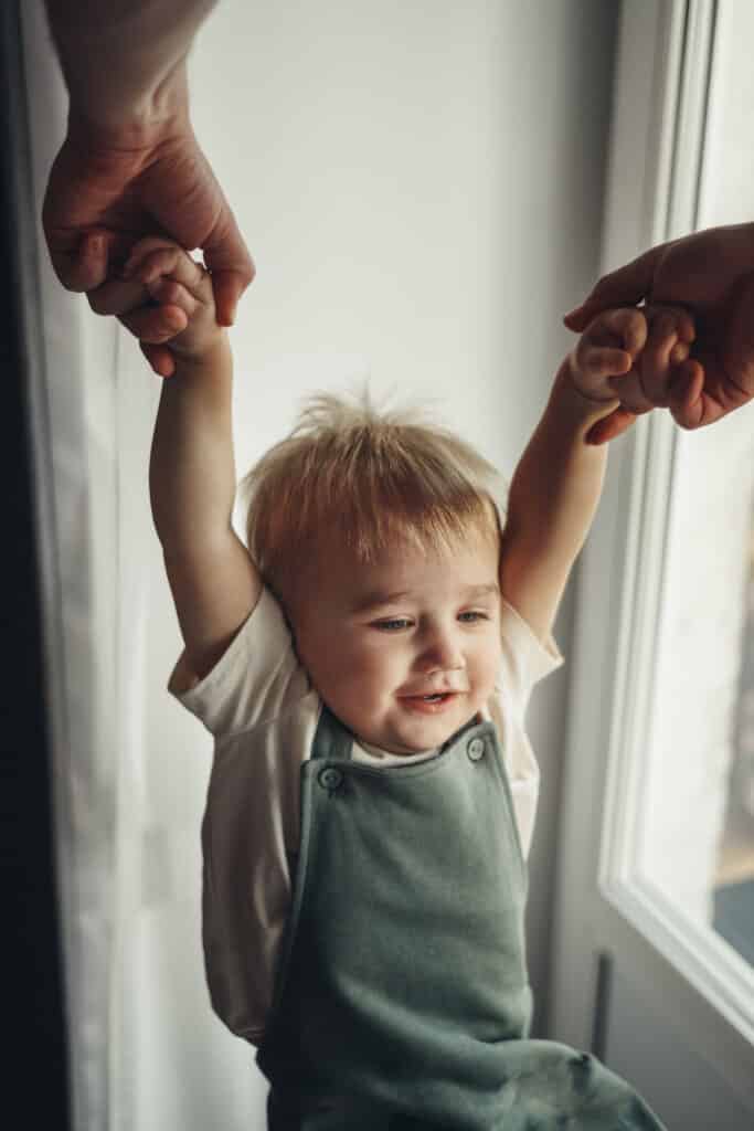A toddler being swung by the hands by a parent, which is a common cause of nursemaid elbow.
