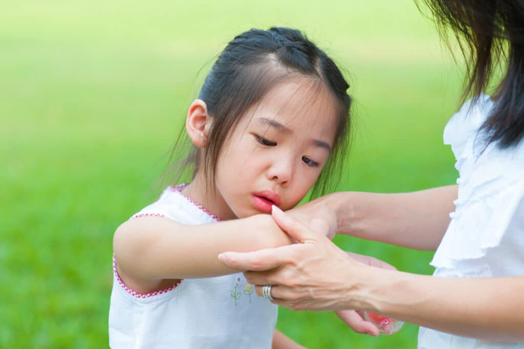 A young child looking at her elbow, which is in pain due to nursemaid elbow.